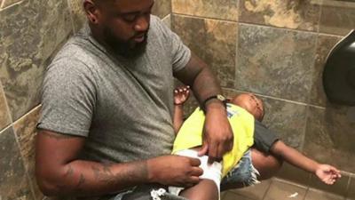 Dad of three, Donte Palmer, squats in a restroom to change his son.