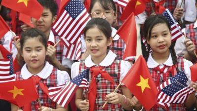 Vietnamese students hold US and Vietnamese flags at a welcoming ceremony for US President Barack Obama