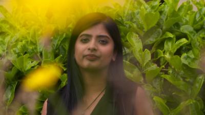 Nyla Khan standing next to flowers