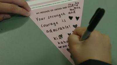 A child writing a banner that says 'your strength and courage is admirable'