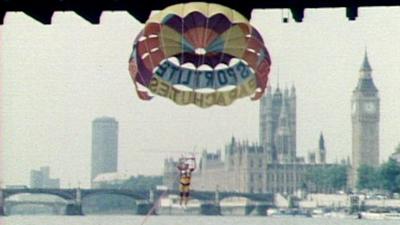 Roy Castle OBE parasailing under Charing Cross Bridge. The houses of parliament can be seen in the background. 