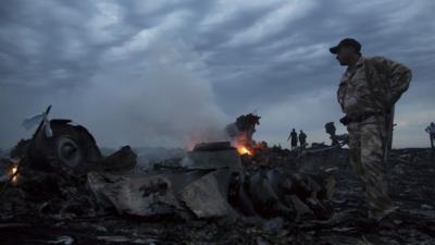 People walk amongst the debris, at the crash site of passenger plane MH17