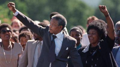 Nelson Mandela and Winnie Mandela raise their arms on his release from prison