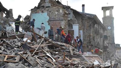 Rescuers work at a collapsed building in Amatrice