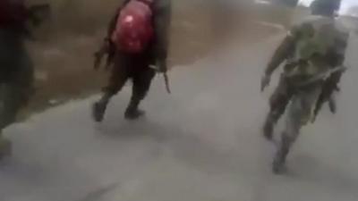 Still from video showing men walking on road