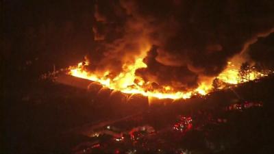 Big fire seen from above, with fire engines firing water onto the blaze