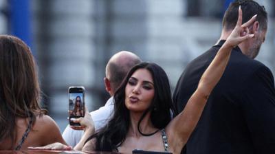 Kim Kardashian poses for a photo on a Venice water taxi. Her fingers are raised in a peace sign.