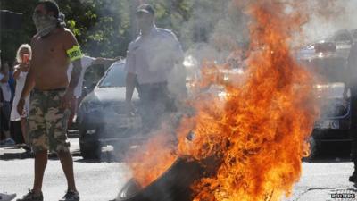 Striking taxi drivers in Paris standing by a burning tyre during a protests against app-based taxi company Uber