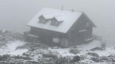 Snow covered cabin surrounded by mist.