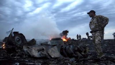 People walk amongst the debris, at the crash site of passenger plane MH17