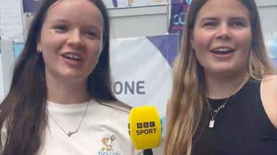 Two women looking into camera and holding BBC Sport-branded microphone