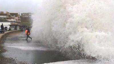 Man carrying child hit by wave