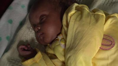 Baby girl under yellow duvet