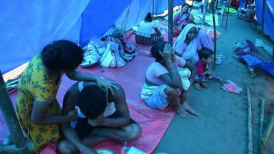 Displaced residents sit in a tent crying