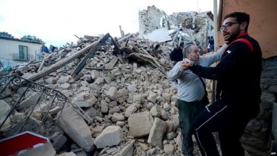 Residents stand among damaged buildings in Amatrice