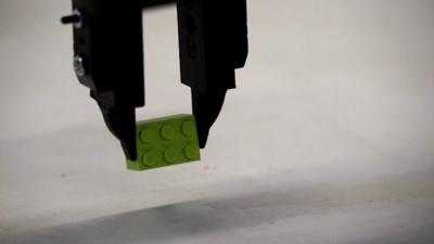 Robot arm picks up a lego brick