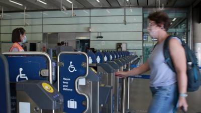 A woman wearing a mask approaches a ticket barrier at St Pancras station