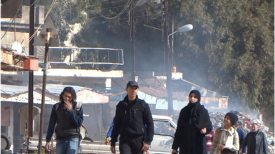 Residents in al-Waer district in Homs walk in a war-ravaged street