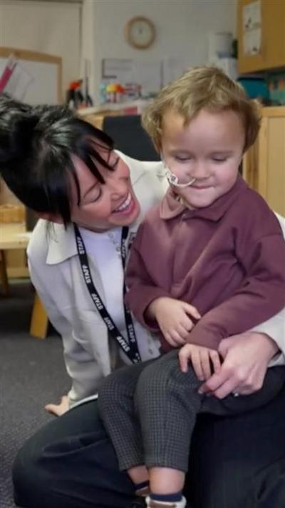 A young boy sat on the lap of a woman smiling with black hair.