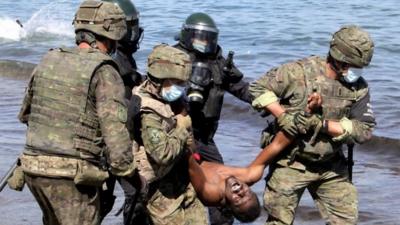 Migrant being carried away by soldiers