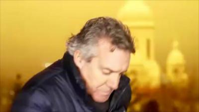 CBS News correspondent Charlie D'Agata takes cover as an explosion lights up Kyiv's sky