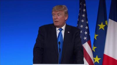 Trump stands at podium during Paris press conference