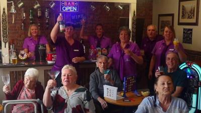 Residents and staff raise their glasses at the care home bar