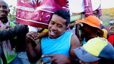 Man holds coffin wrapped in silk cloth