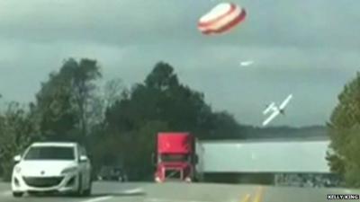 Plane and parachute descending towards motorway