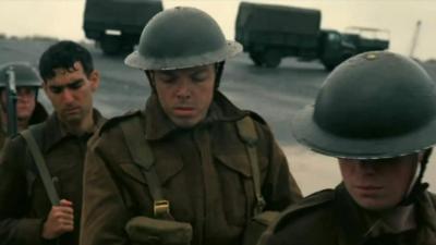 Soldiers standing on a beach in a scene from Dunkirk