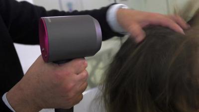 A man drying hair using a Dyson hairdryer