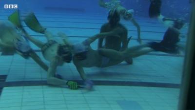 People playing underwater hockey