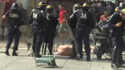 Riot police with injured man on ground