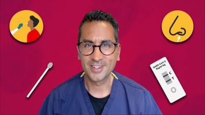 Dr Carter Singh surrounded by the items of a lateral flow test kit