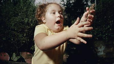 Girl trying to keep hold of a frog