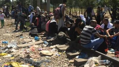 Migrants sitting on train tracks as they wait to be let into Macedonia