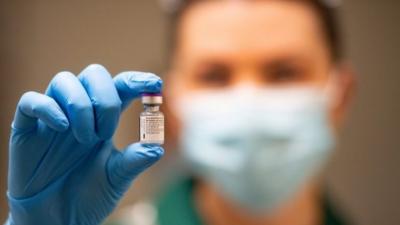 Nurse holds phial of vaccine