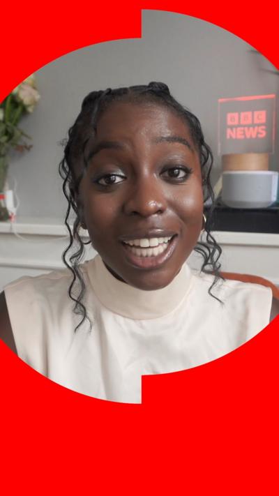 Reporter Jonelle Awomoyi is wearing a white sleeveless turtleneck. She has curly black hair. She is holding a BBC button mic.