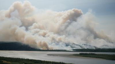 Smoke from a fire drifts over a river in Siberia