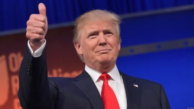 Donald Trump flashes the thumbs-up as he arrives on stage for the start of the Republican presidential debate 6 August 2015