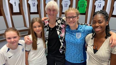 Young footballers standing with Baroness Sue Campbell and NR's Shanequa