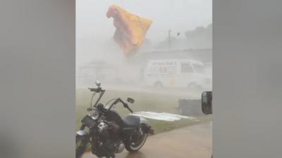 A bouncy castle soars into the air above a motorbike and minivan.