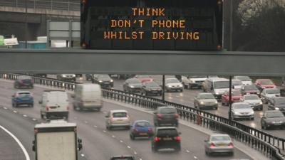 'Think Don't Phone Whilst Driving' sign on motorway