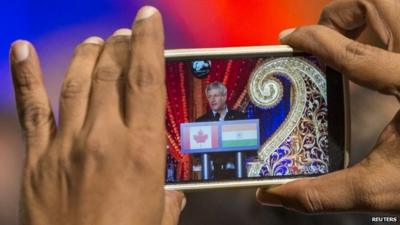 A man takes a picture as Canada's Prime Minister Stephen Harper speaks at a rally with the South Asian community in Ontario