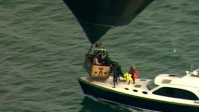 People in hot air balloon basket given life jackets from boat