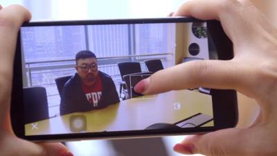 A woman takes a photo of a man using an app being developed by Tencent