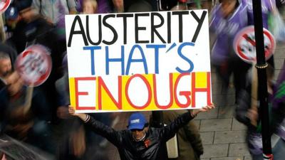 A protester with a placard that reads austerity that's enough