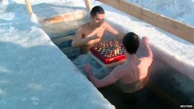 Two contestants play chess in a freezing pool.