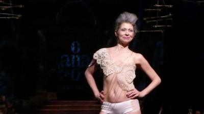 A breast cancer survivor smiles on the catwalk at New York Fashion Week