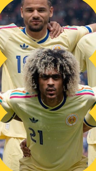 Two players wearing a yellow Curacao football shirt.